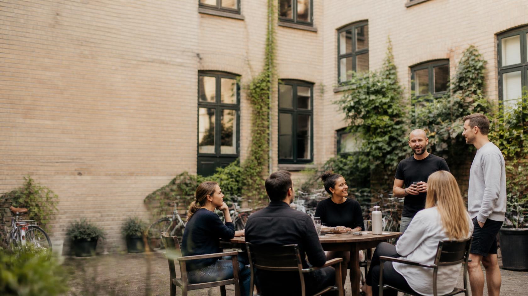 Andelshavere sidder sammen om et bord i gården i en andelsboligforening